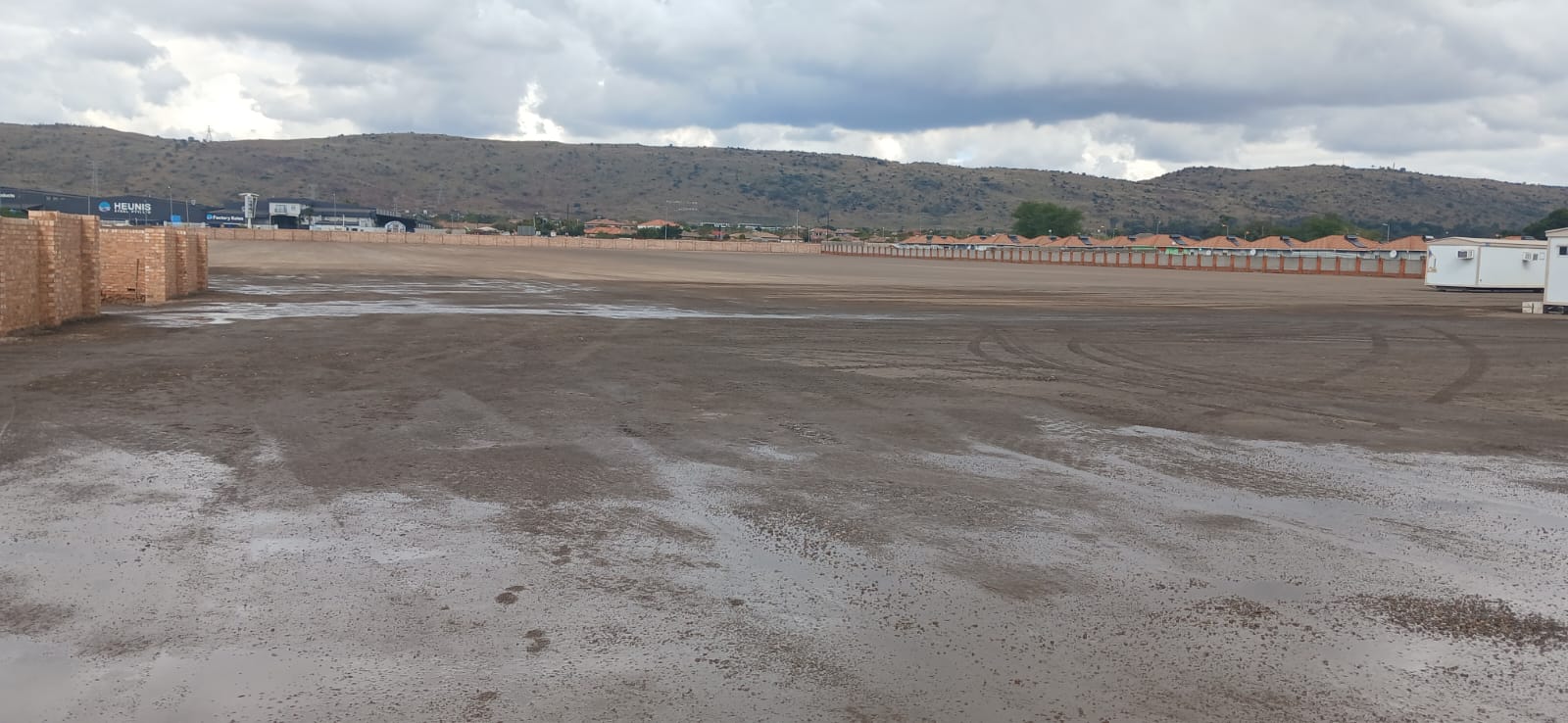A large cleared, graded, and leveled dirt field prepared for construction